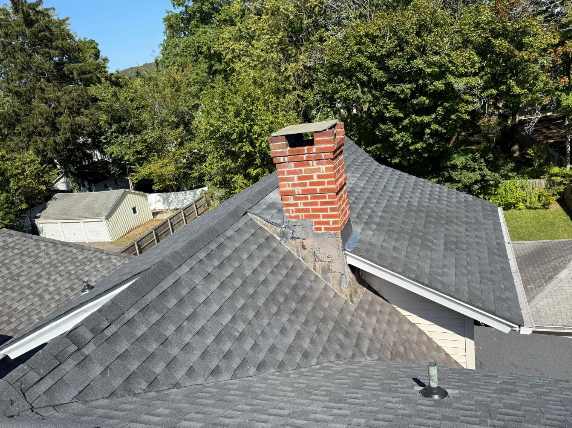 Completed roof with new shingles and brick chimney